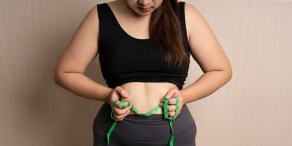 woman holding her belly with a tape measure on her hand