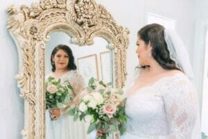 a plus-size woman in her wedding dress looking at the mirror