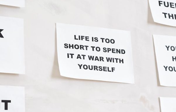a quote that says: "LIFE IS TOO SHORT TO SPEND IT AT WAR WITH YOURSELF" written in a white bond paper