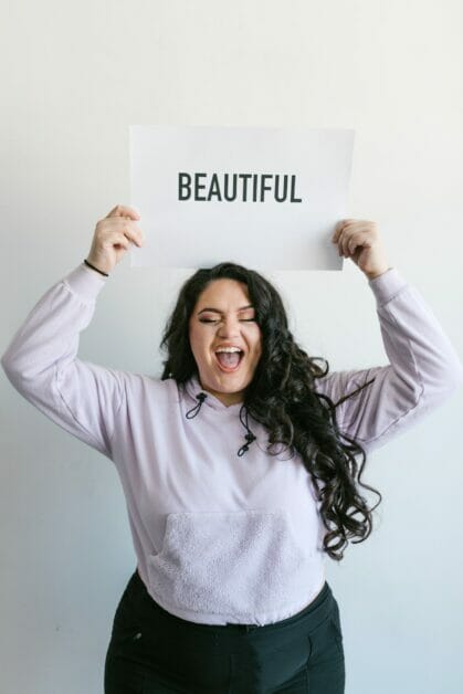 a woman holding a placard that says: "BEAUTIFUL"