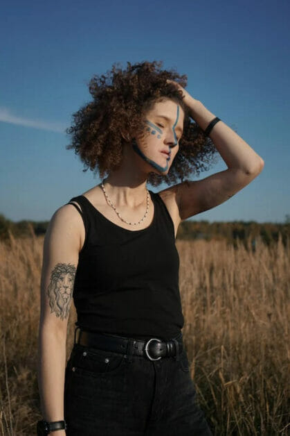 a woman with a lion tattoo on her right inner arm posing under the sun