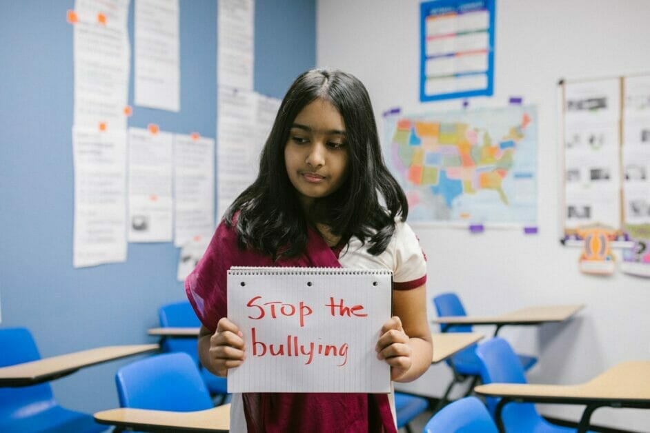 a young girl holding a sign with a message: stop the bullying