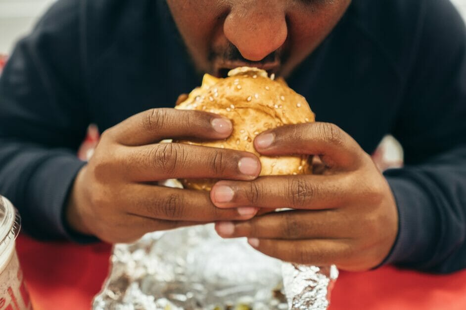 man eating a handful of burger