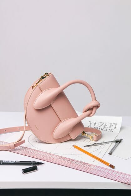 pink small bag on top of paper with measuring tool, pencil, and pen
