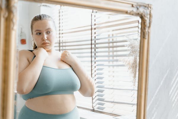 plus-size woman wearing yoga outfit looking at the mirror