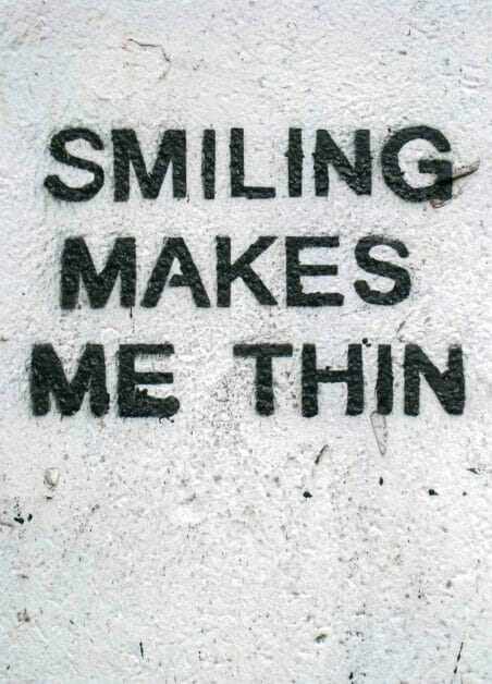 smiling makes me thin written on a white wall