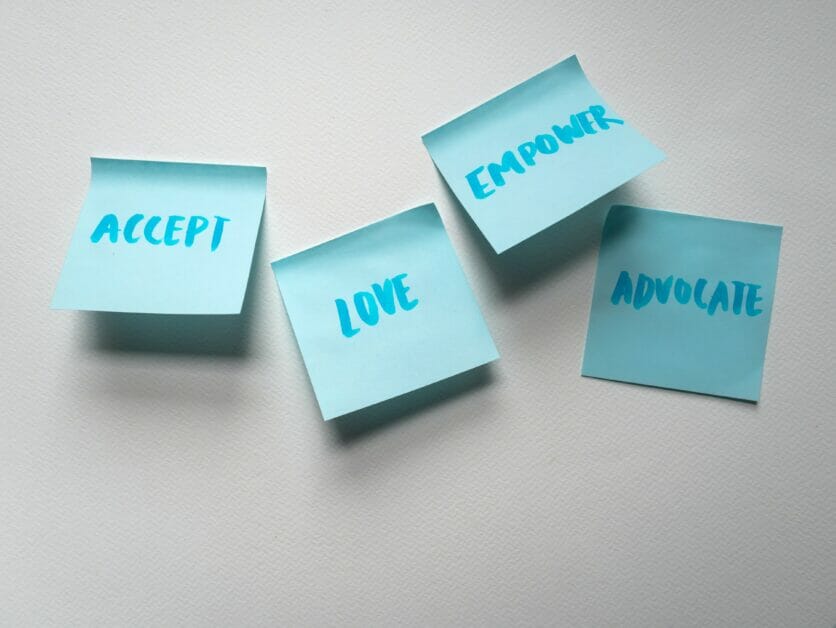 sticky notes on the wall with "accept", "love", "empower", and "advocate" written on it