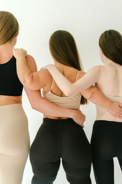 three women in their gym wear posing with their back on the camera