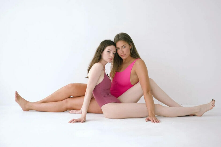 two women model posing in pink and maroon one piece