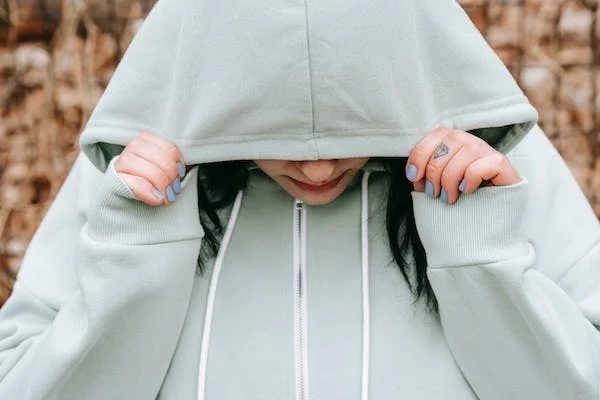 woman covering her face with her hoodie