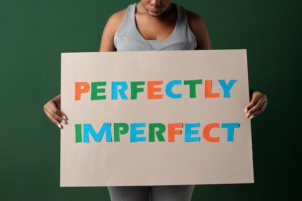 woman holding a placard with quotes "perfectly imperfect"