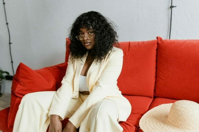 woman seating at a red couch wearing her cream 3 piece suit