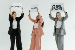 3 women in suit holding a paper with messages about empowering women