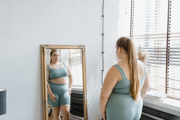 a plus-size woman in her yoga attire looking at the full body mirror