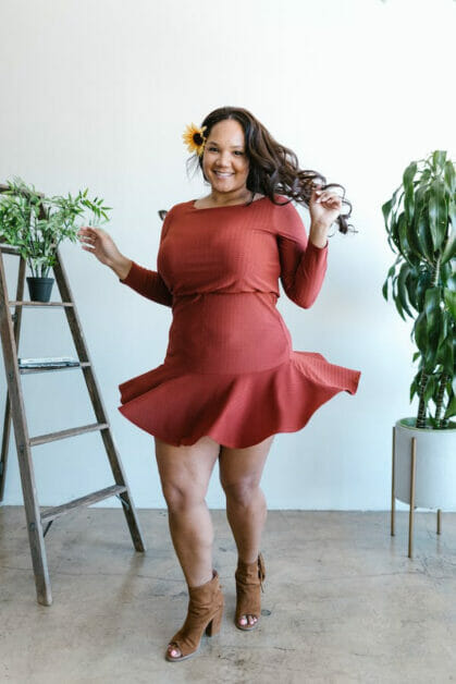 a plus-size woman weaing a red peplum dress paired with brown sandals with heels
