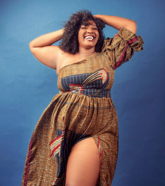 woman in plus-size all smiles wearing an off shoulder maxi dress with slit on the left leg