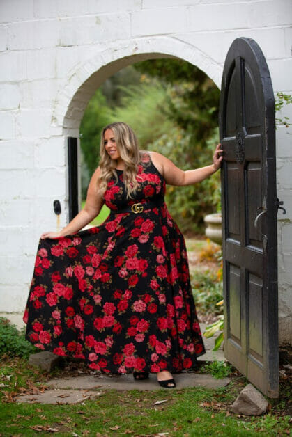woman in plus size wearing a flower print flowing maxi dress accessorize with belt